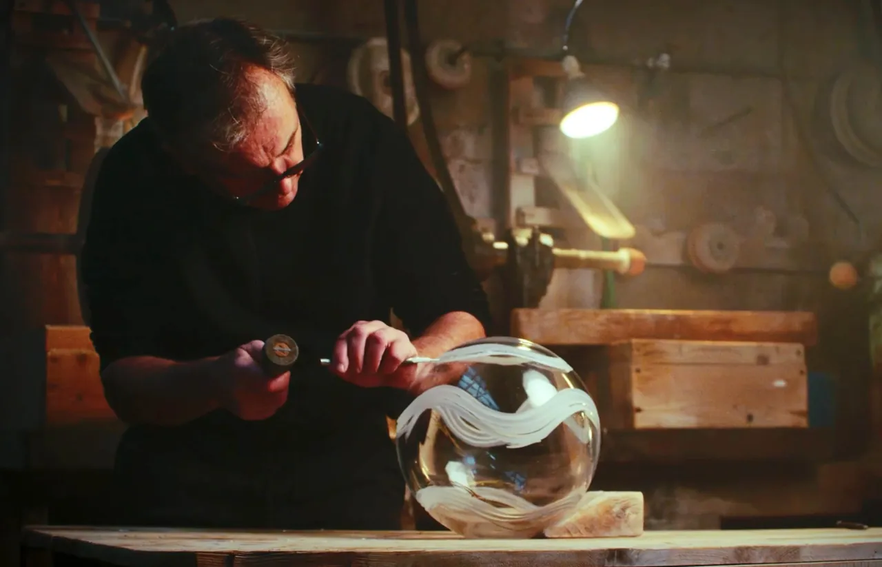 Artisan taillant le cristal à la lumière de l'atelier
